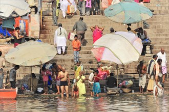 People going about daily activities such as bathing and washing clothes by a river, Varanasi, Uttar