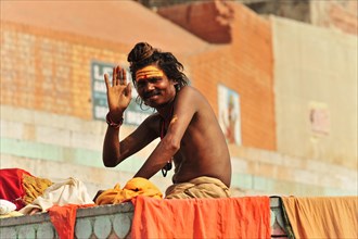 A sadhu at the ghats of Varanasi greets with a painted face and traditional clothing, Varanasi,