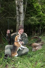 Hunter with hunting dog Beagle enjoying the shot, abnormal european roe deer (Capreolus capreolus)