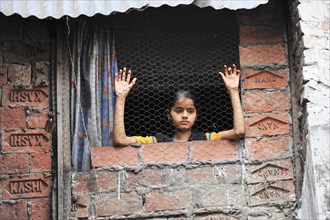 Young girl looking thoughtfully out of a window with brick surround, Varanasi, Uttar Pradesh,