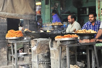 Street vendor preparing deep-fried jalebis and samosas in large pans, Varanasi, Uttar Pradesh,