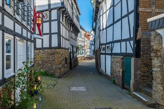 Historic half-timbered houses in an alley with cobblestones and blue sky, Old Town, Hattingen,
