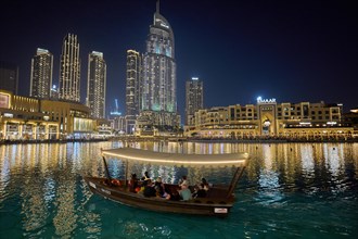 Dubai, United Arab Emirates, AsiaTourists ride in a boat in front of the skyscraper backdrop at
