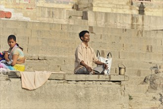 Single person praying on the steps of the ghats in the morning light, Varanasi, Uttar Pradesh,