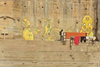 Fresh murals on the ghats of a river, people going about their daily routines, Varanasi, Uttar