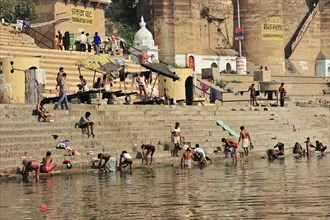 People bathing and socialising at the busy ghats of an Indian river, Varanasi, Uttar Pradesh,