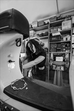 Woman mechanic focusing on repairing the inside of a moped italian vintage scooter in a workshop,