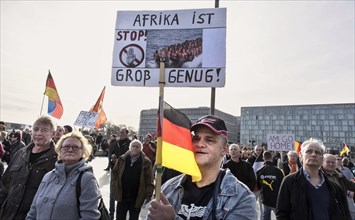 A participant in the Merkel muss weg demonstration wears an AFD cap and holds a sign reading Afrika