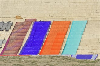 Colourful textiles are laid out to dry on the banks of a river, Varanasi, Uttar Pradesh, India,