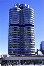 Four cylindrical towers of the BMW building under a bright blue sky, BMW WELT, Munich, Germany,