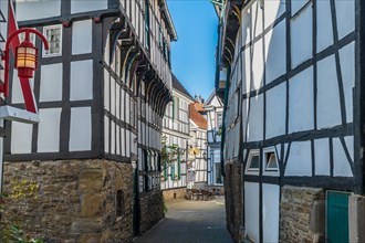 A narrow alley with traditional German half-timbered houses and cobblestones, Old Town, Hattingen,