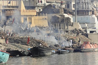 Smoke rises from a traditional funeral fire at the ghats of a river, Varanasi, Uttar Pradesh,