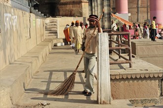 A cleaner sweeps the floor at the ghats of Varanasi in uniform, Varanasi, Uttar Pradesh, India,