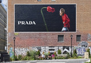 Hand-painted mural, woman with handbag standing in front of flower, advert for PRADA, SoHo