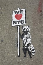 Graffiti on pavement, raccoon holding sign saying We love NYC, SoHo neighbourhood, Manhattan, New