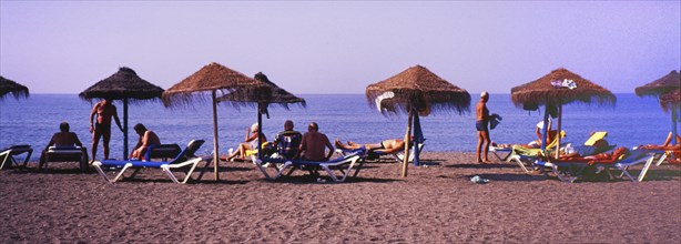 Sunbathers with parasols on the beach in Torre del Mar, Costa del Sol, Malaga province, Andalusia,
