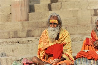 Man in traditional dress meditating on steps in peaceful surroundings, Varanasi, Uttar Pradesh,