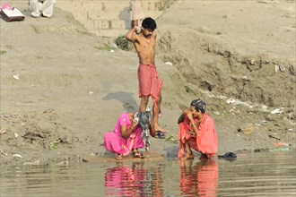 People on the banks of a river during daily washing routines in traditional clothing, Varanasi,