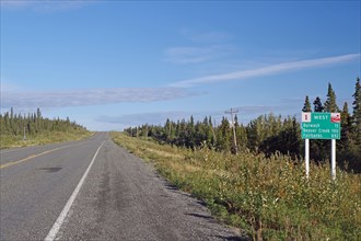 Road leads as endless grades through wilderness, no traffic and one traffic sign, Alaska Highway,