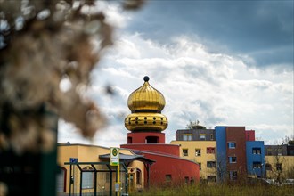 A building with a golden dome, blurred nature in the foreground, urban environment, Hundertwasser