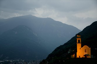 Illuminated Church on the Mountains at Night withStorm Clouds in Bellinzona, Ticino, Switzerland,