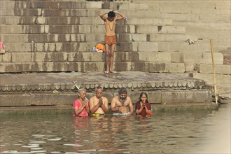 A man and woman in traditional dresses in the shallow water of a river during a ceremony, Varanasi,