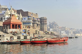 Boats dock at the ghats of a river, with classical Indian architecture in the background, Varanasi,