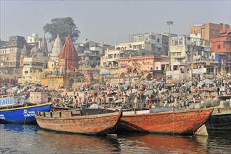 Lively riverside landscape with crowds of people and boats in the hazy background, Varanasi, Uttar