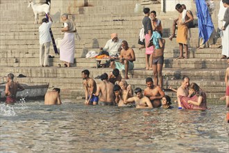 Group of people bathing and socialising in the water of a river, Varanasi, Uttar Pradesh, India,