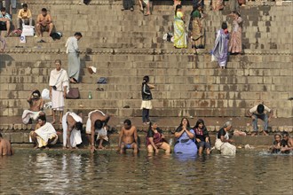 People bathing and washing on the steps of a river, some in traditional dress, Varanasi, Uttar