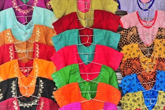Row of colourful embroidered dresses on display at a market, Varanasi, Uttar Pradesh, India, Asia
