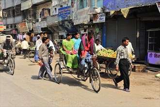 Busy urban scene with rickshaws and pedestrians next to street shops, Varanasi, Uttar Pradesh,