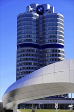 Striking tower with blue BMW symbol and futuristic architecture under a blue sky, BMW WELT, Munich,