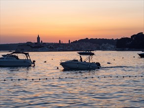 Boats anchoring in a bay, church towers, evening mood after sunset over Rab, town of Rab, island of