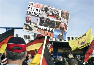 A participant in the Merkel muss weg demonstration holds a sign reading Gib Islam keine Chance.