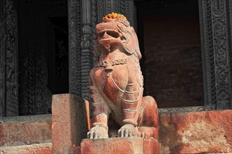Stone lion statue with flower necklace in front of a carved temple background, Varanasi, Uttar