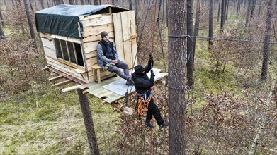 A climate activist pulls herself up a rope to a tree house in the Gruenheide forest. The activist