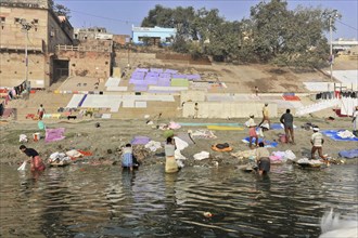 People washing clothes in a river against a colourful backdrop, Varanasi, Uttar Pradesh, India,