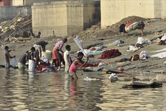 People washing and spreading clothes on the bank of a river, everyday scene with labour activity,