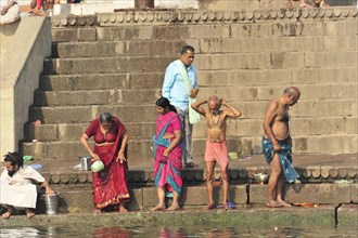 People performing ritual ablutions on a river bank in the early morning, Varanasi, Uttar Pradesh,