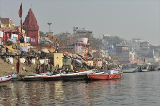 View of boat-filled ghats and a riverside temple, sign of religious activity, Varanasi, Uttar