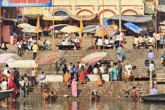 People at the ghats of a river under umbrellas with urban background, Varanasi, Uttar Pradesh,