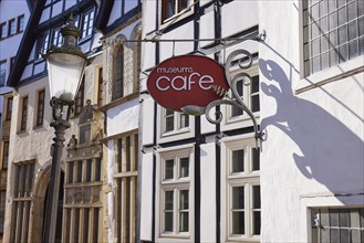 Historic facades, lantern and sign for the museum cafe in backlighting in the Schnurrviertel in the