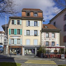 Old pastel-coloured houses with white windows and wooden shutters and the Cafe Vieil Ouchy in the