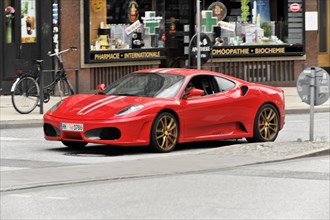 A red Ferrari sports car driving on a city street, Hamburg, Hanseatic City of Hamburg, Germany,