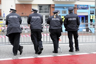 Four police officers in uniform watching a cordon on a street, Hamburg, Hanseatic City of Hamburg,