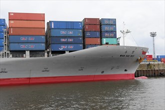 Bow of a large container ship WAN HAI 501 with red stripe and stacked containers, Hamburg,