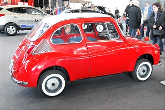 A small red vintage Subaru 360 with a white roof in an exhibition hall, Stuttgart Trade Fair