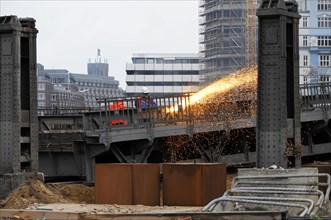 Worker on construction site during welding work with sparks flying in the twilight, Hamburg,