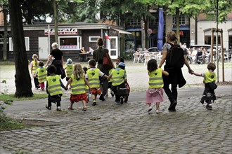 Toddlers in high-visibility waistcoats walking in a pedestrian zone, Hamburg, Hanseatic City of